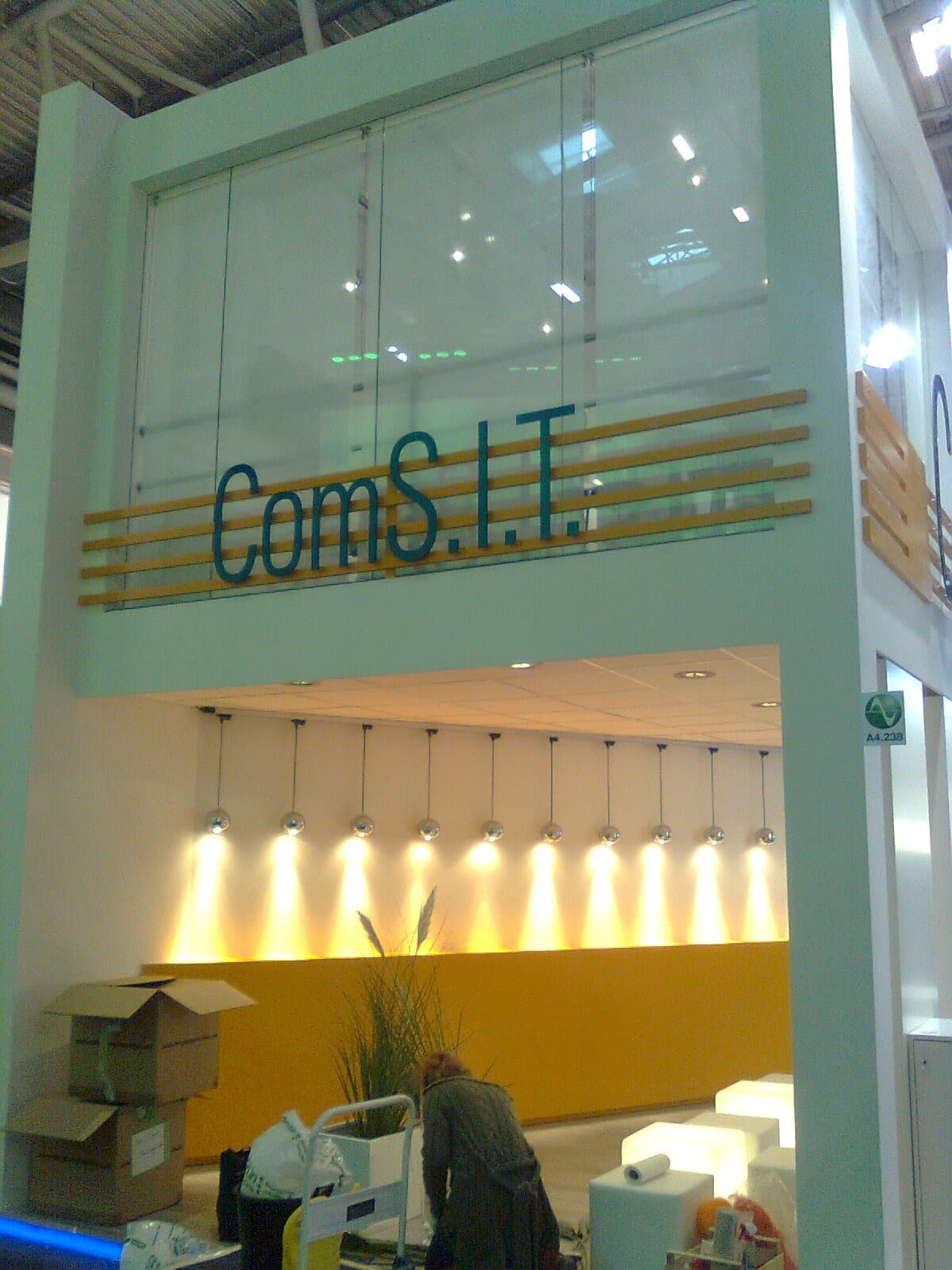 ComS.I.T.-Messestand mit gläserner Obergeschoss-Box und beleuchteter Empfangstheke