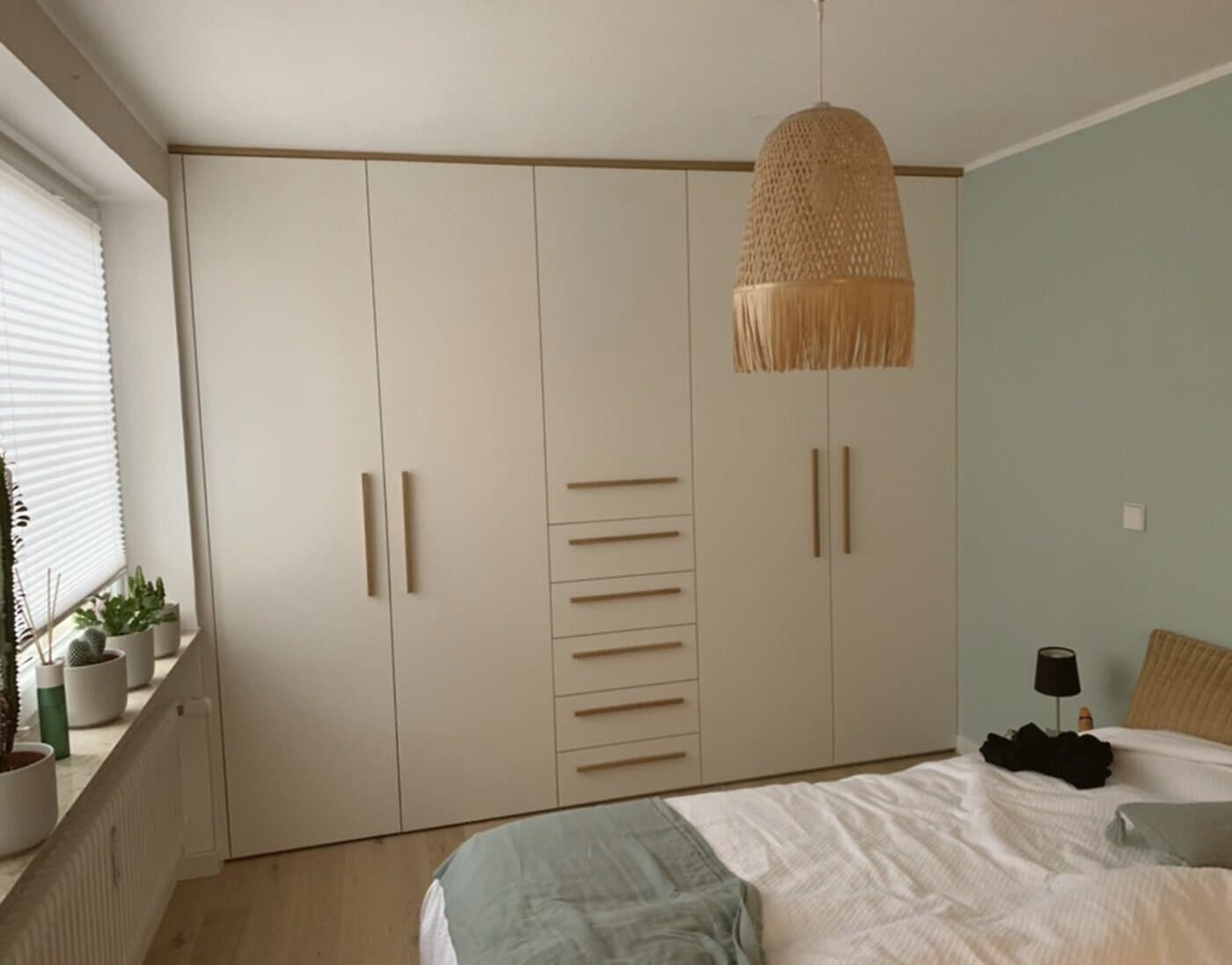 Cremefarbener Einbauschrank mit Eiche-Griffen vor einer Salbeiwand
